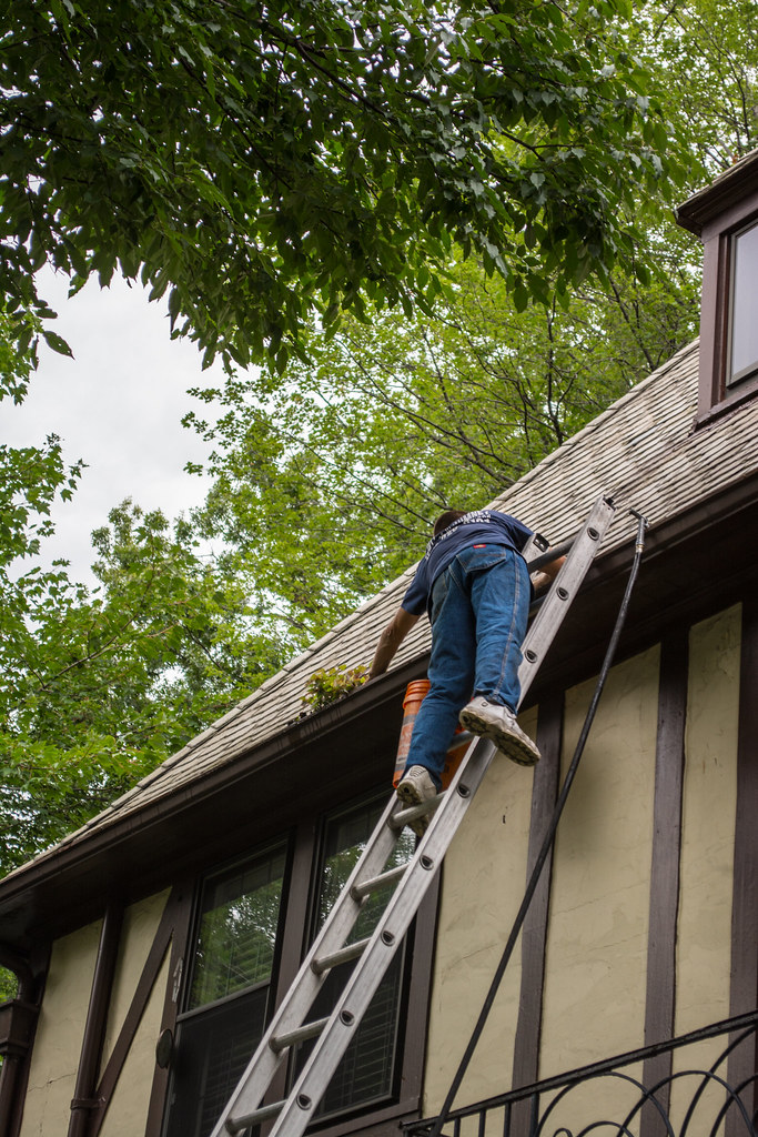 Tradesperson clearing debris from a roof gutter