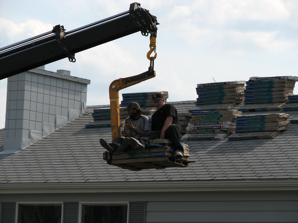 Roofing materials being lifted onto a house roof