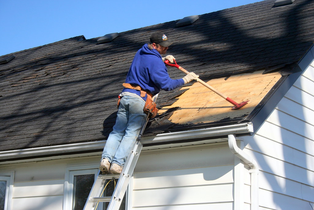 Roofer stripping old shingles during a roof repair